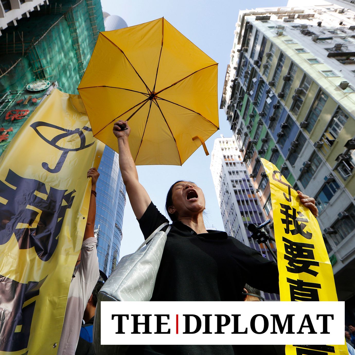 A pro-democracy protester chants umbrella and a yellow banner at an occupied area before the barricade is removed in Mong Kok district of Hong Kong Tuesday, Nov. 25, 2014.