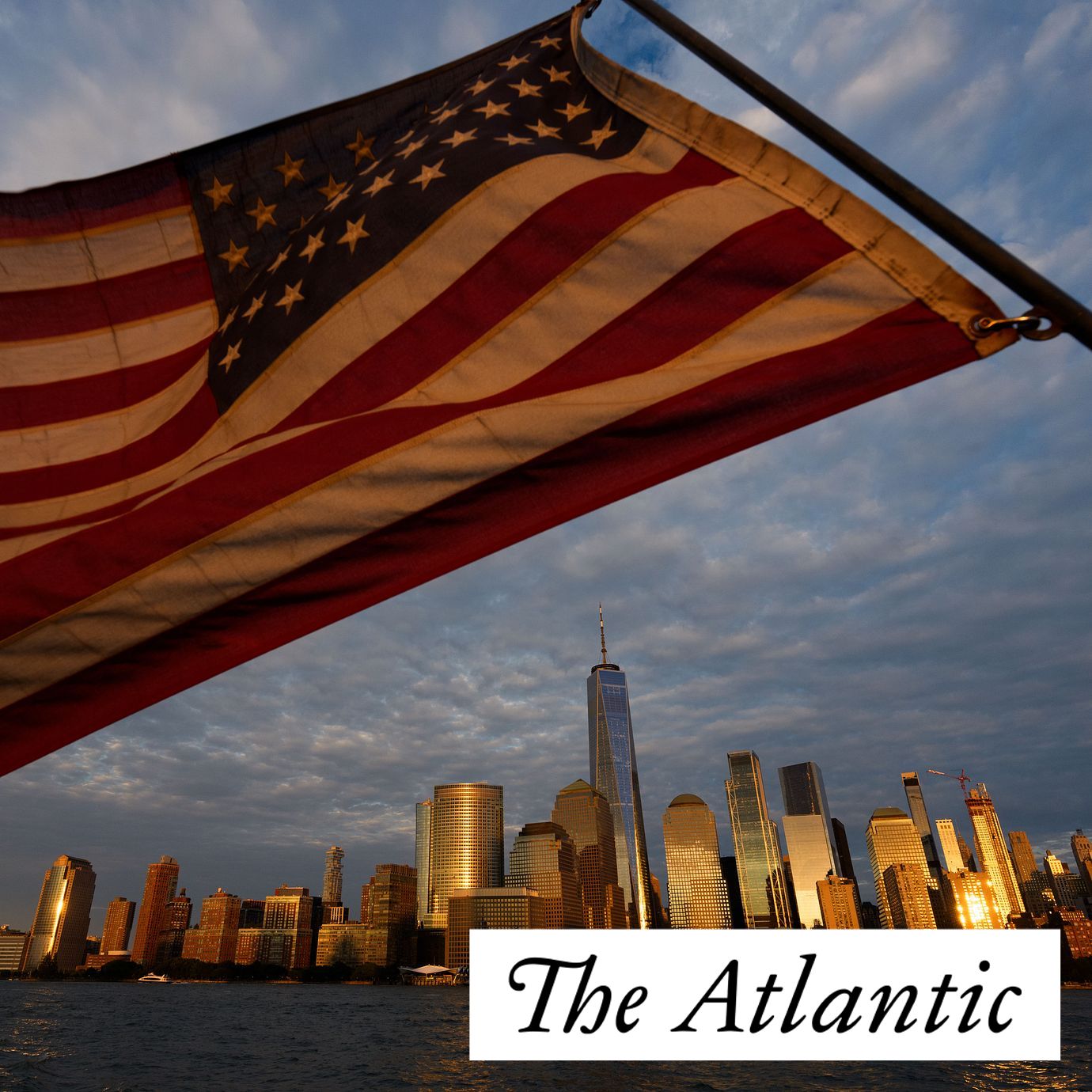 An American flag flies, with the lower Manhattan skyline in background.
