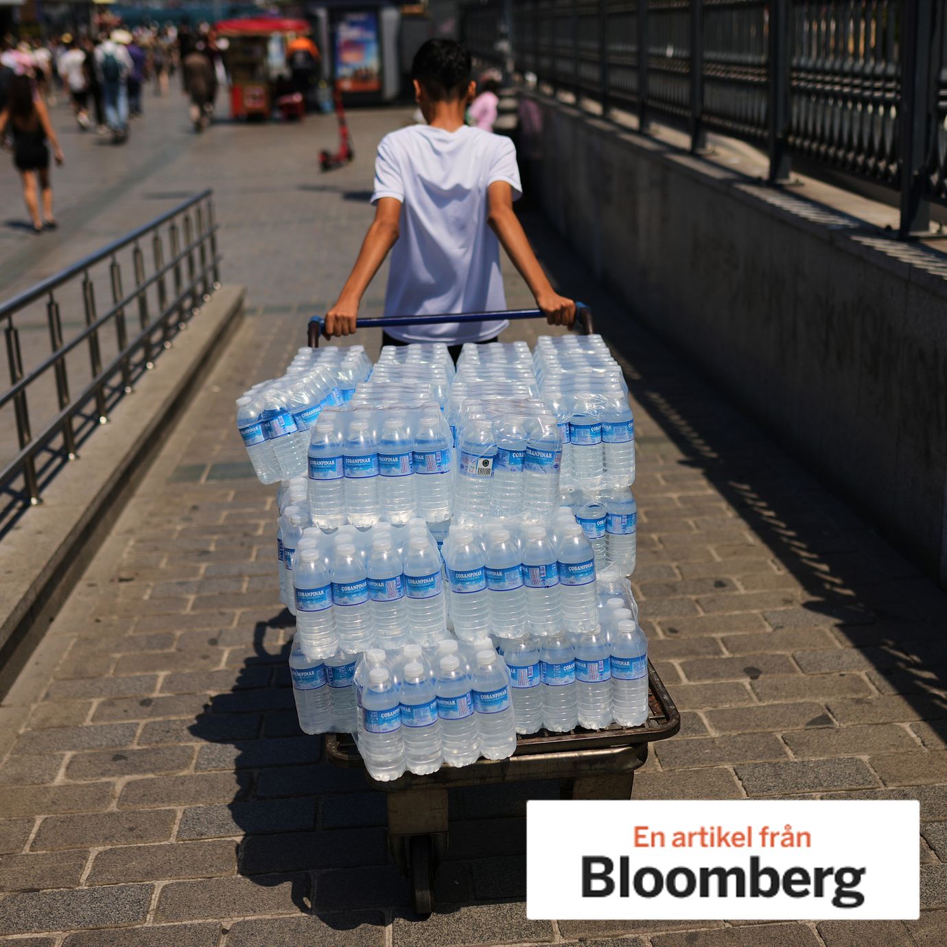 A young man delivers plastic bottles of water during a hot day in Istanbul, 2026.