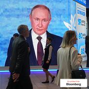 People walk past a screen with an image of Russian President Vladimir Putin at the St. Petersburg International Economic Forum, 2026.