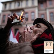 A man lights on a cigarette using fake U.S. dollar notes during an anti-U.S. and anti-Israeli rally in support of the Iranian government, in Istanbul, Turkey, 2026.